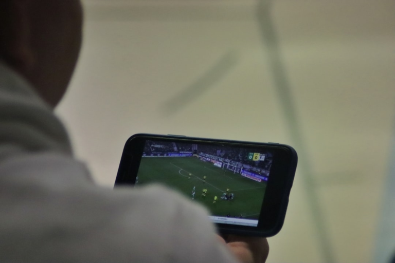 a man is playing a soccer game on his phone — Foto por (Augustin-Foto) Jonas Augustin na Unsplash