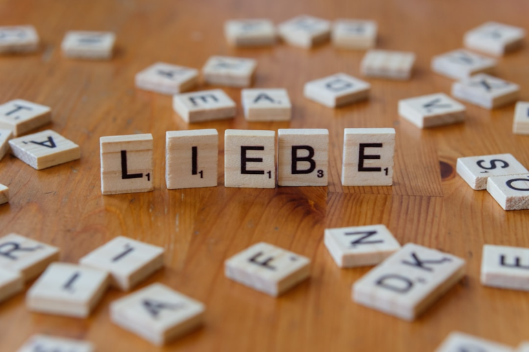A wooden table topped with blocks that spell out the word liebe — Foto por Markus Winkler na Unsplash